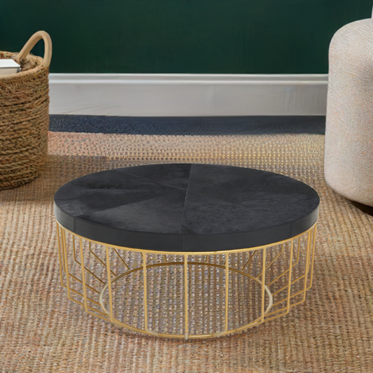 Round coffee table has a black hair on hide leather tabletop with gold iron base.